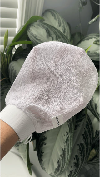 Wildpier Deep Exfoliating Glove held in a bright bathroom